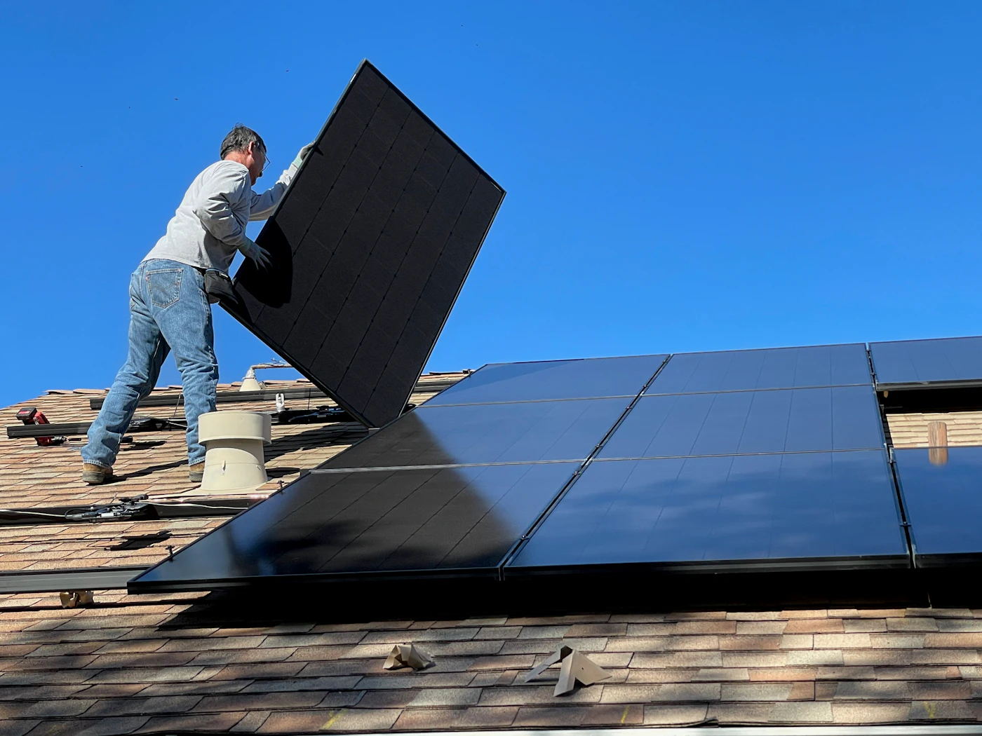 Monteur installiert ein Photovoltaikmodul auf einem Hausdach